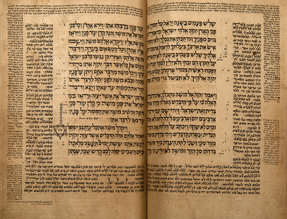 A book opened up to two pages filled with Hebrew letters, the Judeo-Arabic Tanach, the Tafsir Rasag.